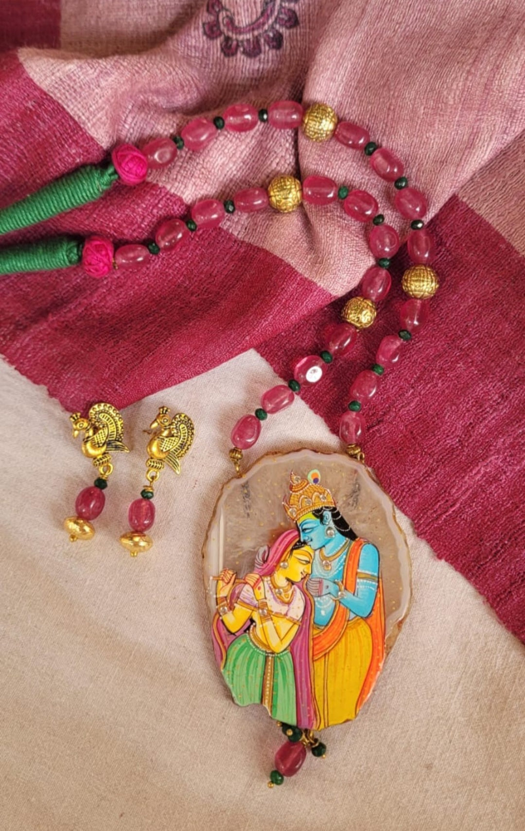 Colorful necklace with a pendant featuring a traditional design on a pink fabric background