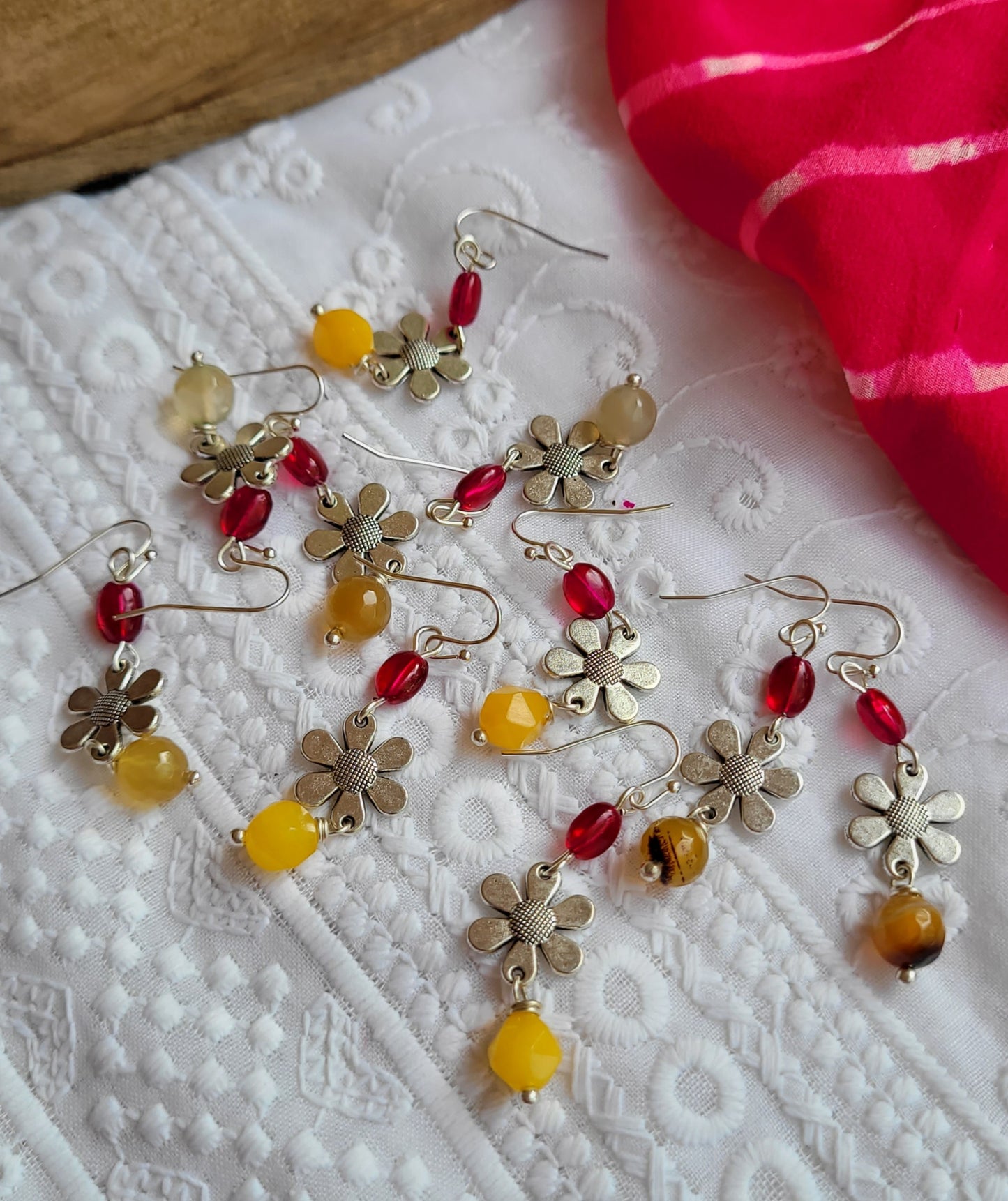 Floral earrings with colorful beads on a textured white surface