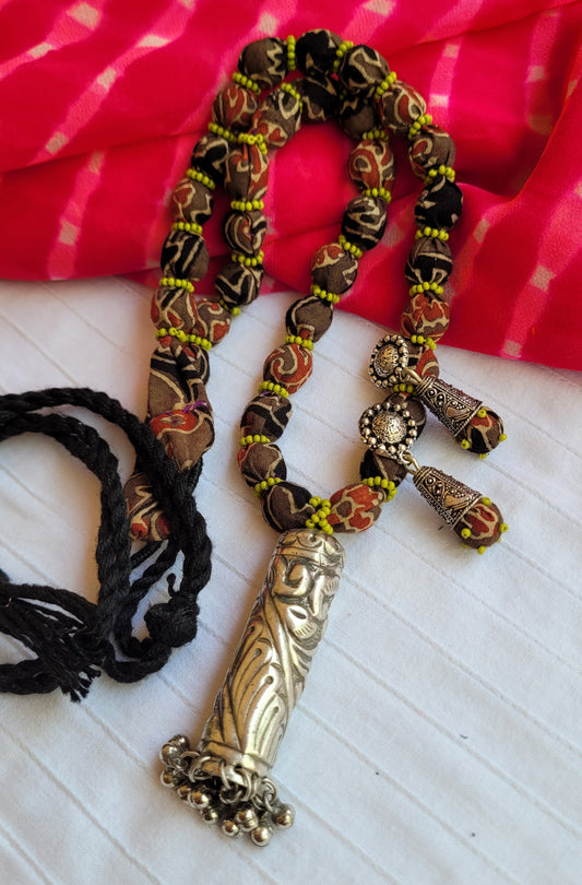 Decorative necklace with intricate design on a red and white striped fabric background