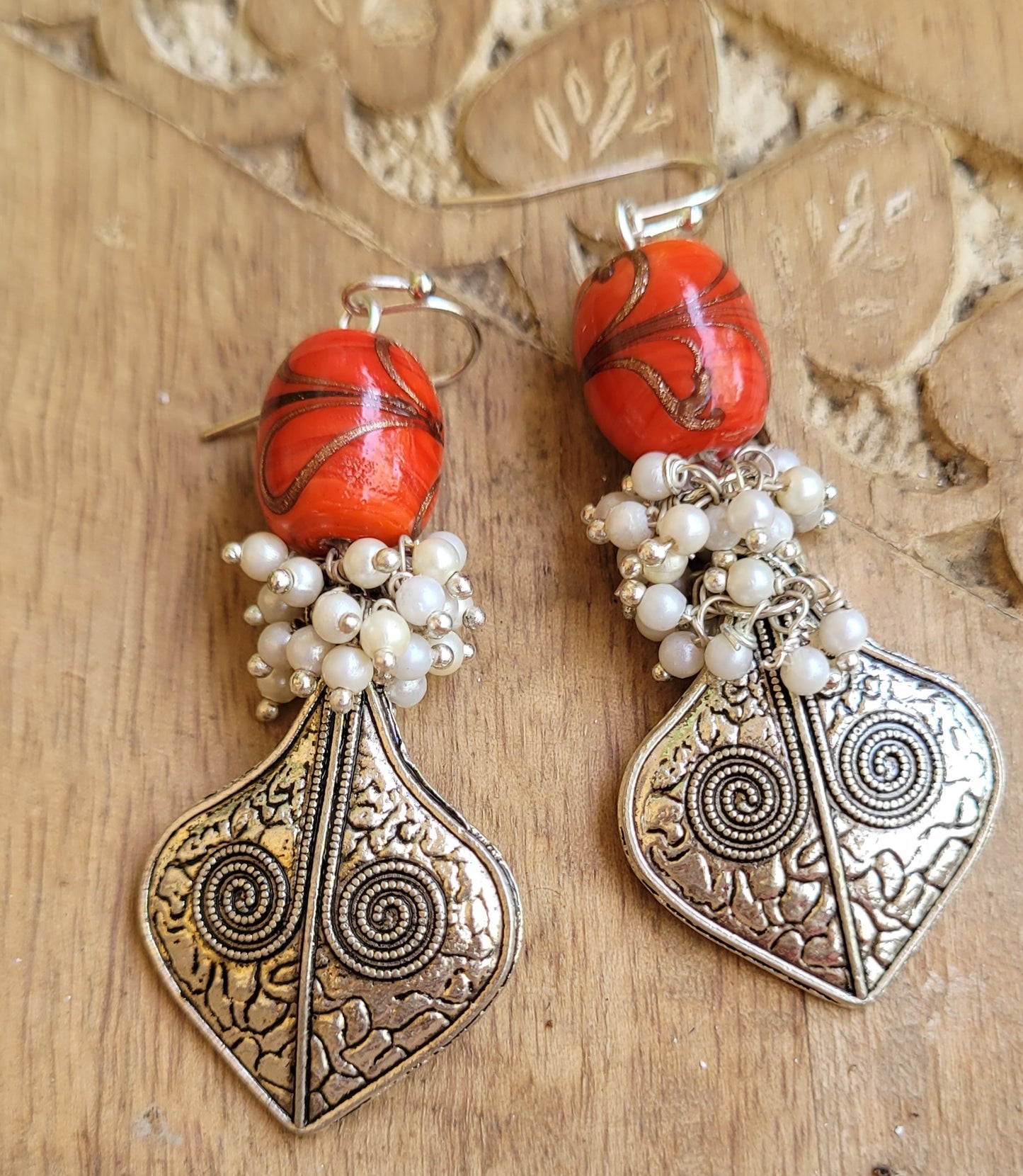 Pair of ornate earrings with red beads and silver designs 