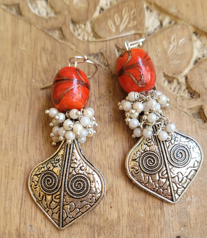 Pair of ornate earrings with red beads and silver designs 