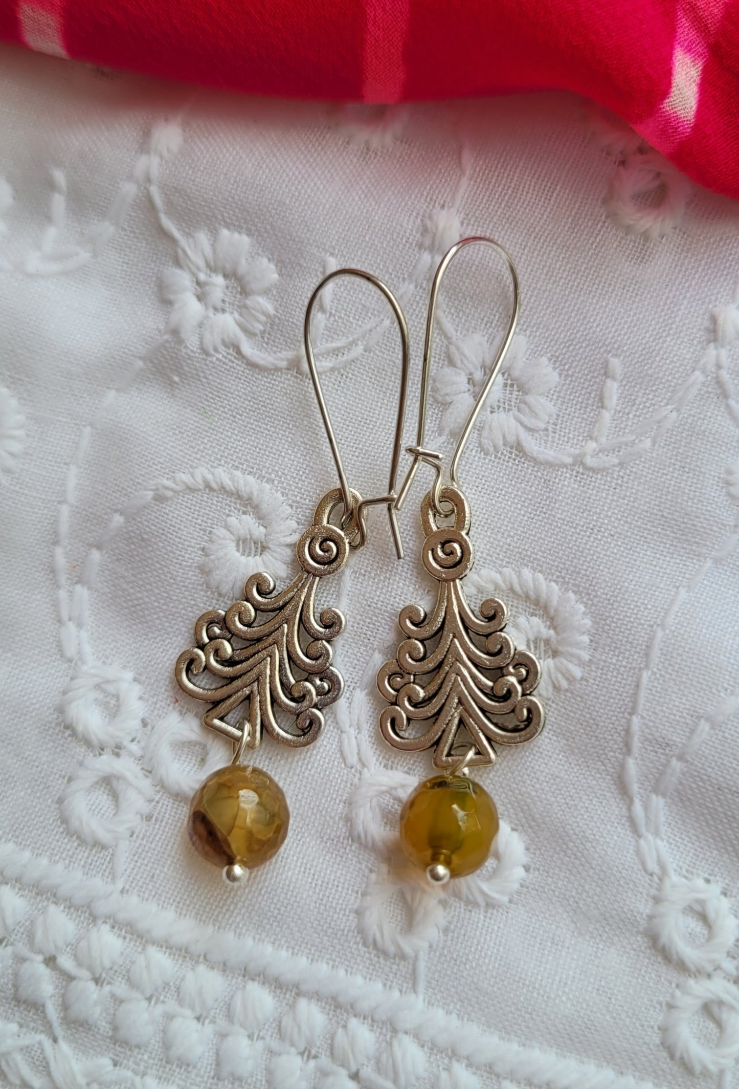 Silver earrings with amber beads on a white lace background