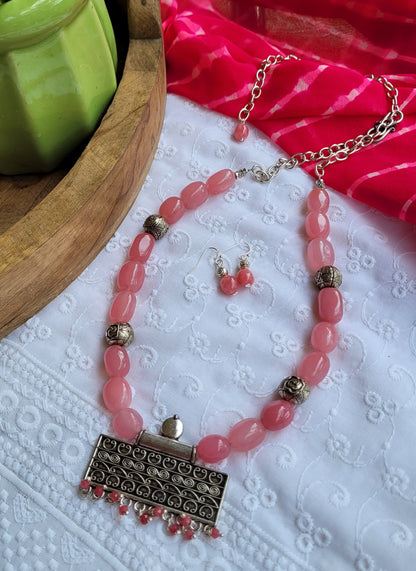 Pink beaded necklace with a silver pendant and matching earrings