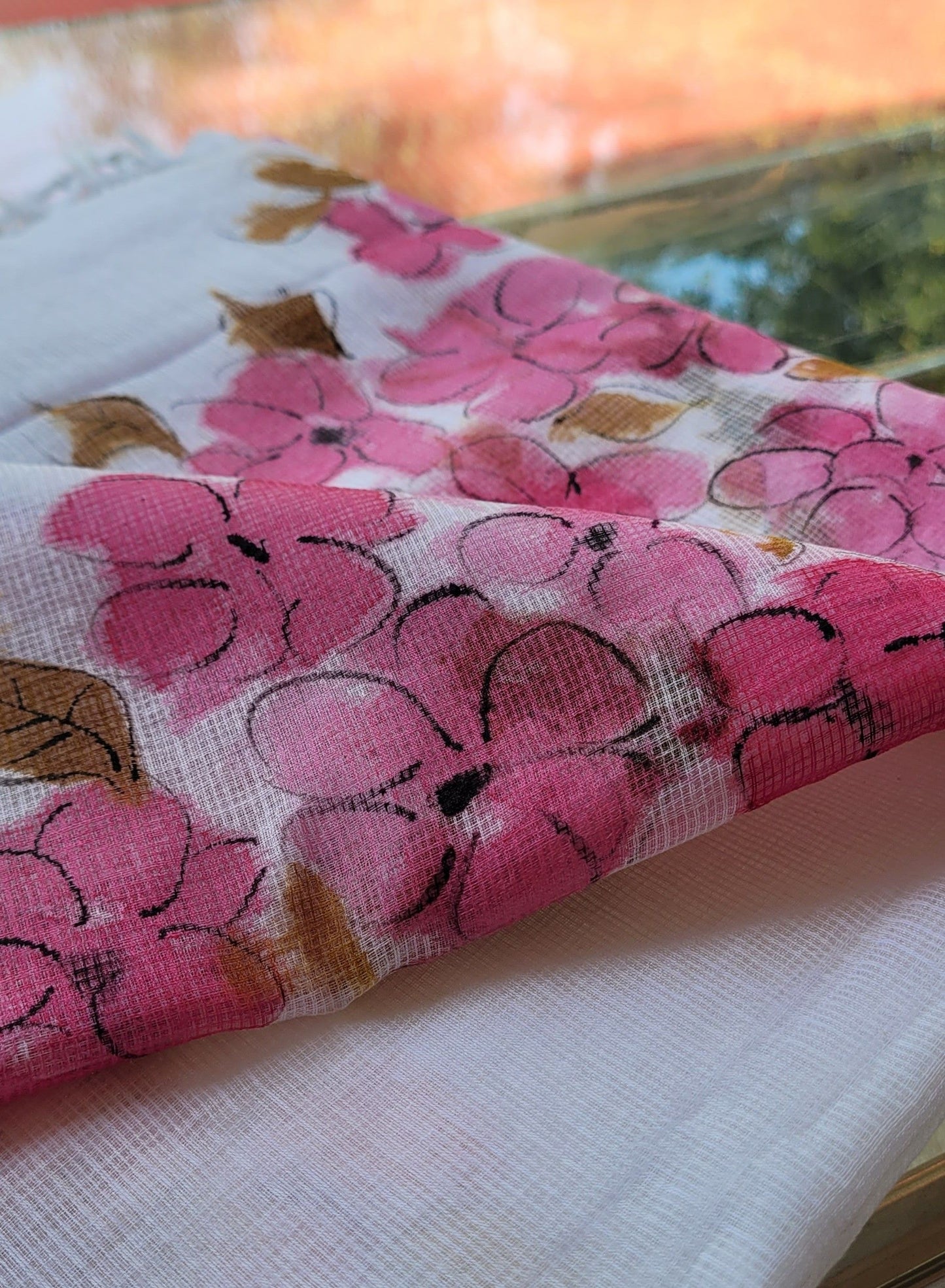 Floral-patterned fabric with pink flowers and green leaves on a white background